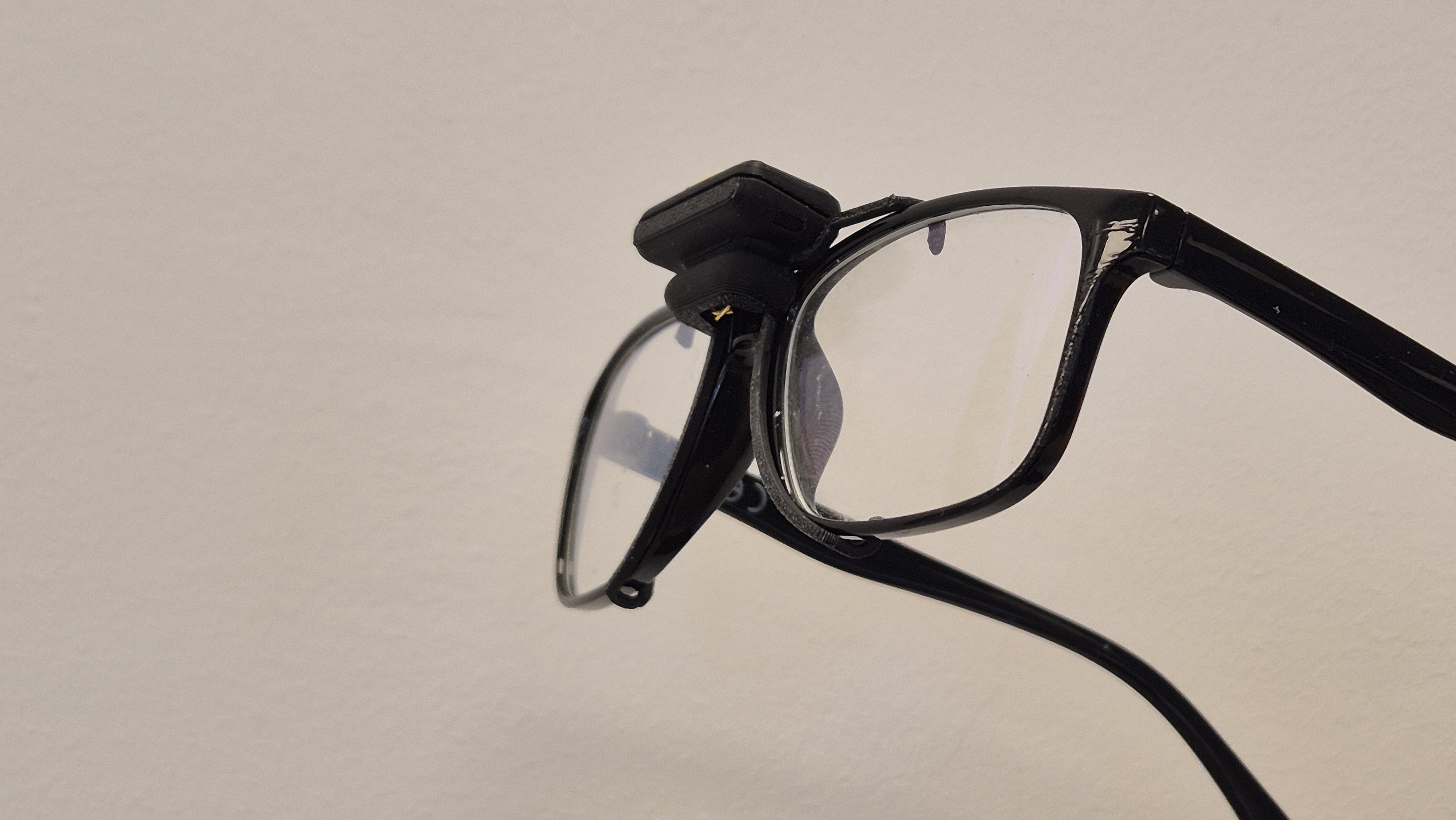 BlinkAid NeuroClips clip-on prototype mounted on standard eyeglasses